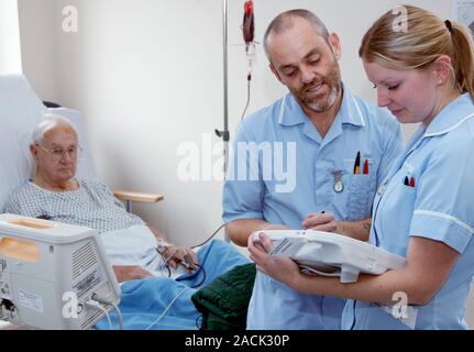 This is a real situation. Image not to be used in a defamatory context. Nurses using handheld computers with the VitalPAC software system installed to Stock Photo