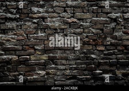 Urban black brick wall texture old masonry background. Gloomy background, black brick wall of dark stone texture. Stock Photo