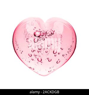 Pink serum gel, heart shape puddle isolated on white backdrop, top view. Squeezed transparent care gel with bubbles close up, macro isolated on white