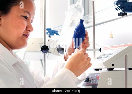 Female scientist wearing a white coat uses equipment during pharmacy research in a laboratory. Stock Photo