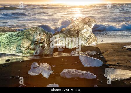 Icebergs on the cost of the black sand beach in the rays of the rising sun,  Jokulsarlon,  southeast Iceland. Stock Photo