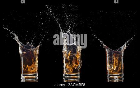 Glasses of whiskey with splash, isolated on black background Stock Photo