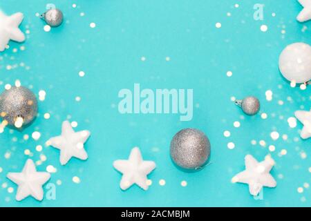 Frame of Christmas decorations on turquoise background, flatlay, overview, with blurred golden festive lights. Christmas time concept. Space for text Stock Photo