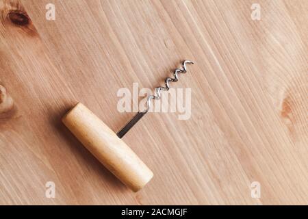 Classic corkscrew lays on a wooden table, top view Stock Photo