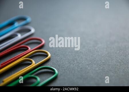 multi-colored paper clips on dark background, stationery. Stock Photo