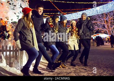 Dancing friends on Christmas fair in night Stock Photo