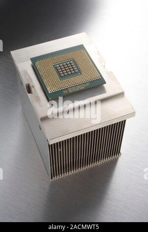 Hafnium-based CPU and heat sink. This computer central processing unit (CPU) is the square element (green and gold), mounted on a larger metal heat si Stock Photo