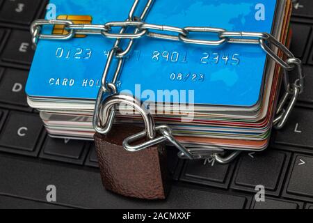 Closed access to credit cards, blocked, lock. A stack of credit cards and a padlock with a chain on a laptop keyboard. Stock Photo