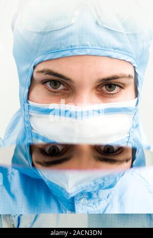 Cleanroom. Close-up of the face of a woman wearing a cleanroom suit. A cleanroom is an environment used in manufacturing or scientific research that h Stock Photo