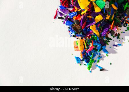 Bright colorful wooden pencil and crayon shavings on white paper background, copy space, creativity and art school concept Stock Photo
