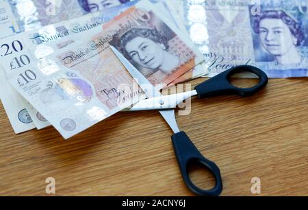 Concept of scissors cutting ten pound note Stock Photo