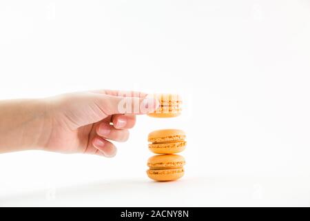 Macaroons on a white background and hand holding one and folding them into a tower, colorful macaroons, selective focus. Stock Photo