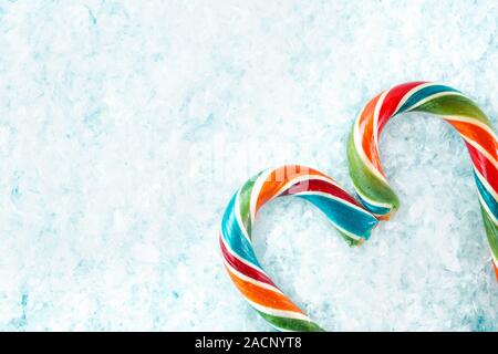 Colorful festive heart shaped Lollipop on white artificial snow background selective focus. Stock Photo