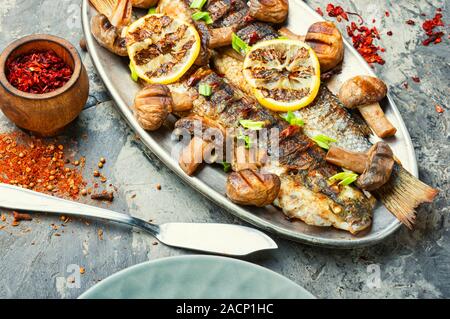 Roasted pelengas fish with mushrooms and lemon.Sea food.Grilled fish with champignon Stock Photo