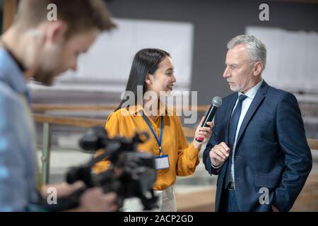 Asian female reporter holding a microphone in her hand Stock Photo