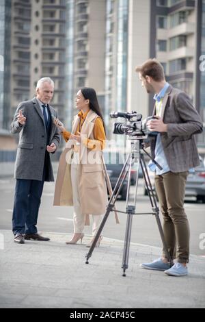 Young cute female reporter talking to a famous businessman Stock Photo