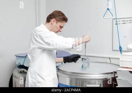 Sperm bank. Laboratory worker retrieving frozen sperm for shipment. This work is being carried out at Cryos International Sperm Bank, Aarhus, Denmark. Stock Photo