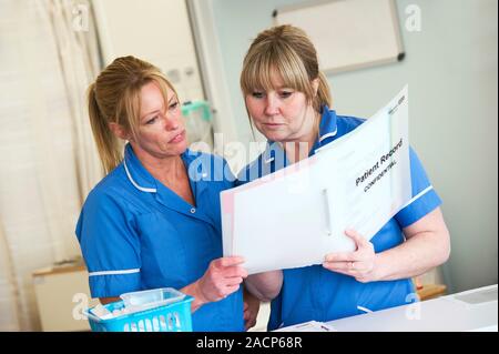 Nurses discussing patient records on a ward. Stock Photo