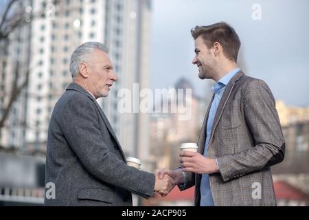 Young businessman and his mature mentor shaking hands Stock Photo