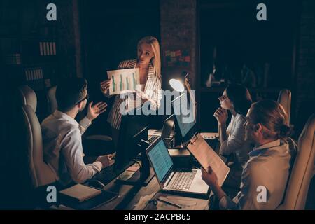 Nice attractive focused skilled experienced coworkers experts specialists developing company department statistics income data analysis at night at Stock Photo