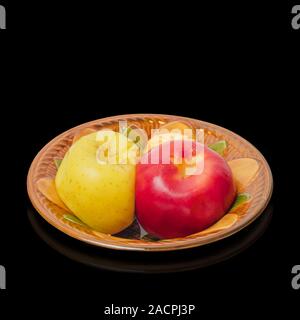 Two baked apples in a ceramic bowl on a black background Stock Photo