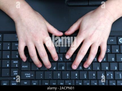 Computer use. Close-up of a child's hands on a keyboard. Stock Photo