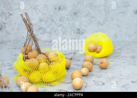 Exotic longan fruit in a string bag on a gray background. Place for text. Close-up. Copy space. Top view. Stock Photo