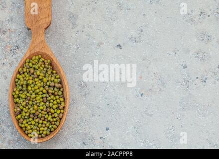 green beans in a wooden spoon, gray background, closeup, copy space. Vigna radiata Stock Photo