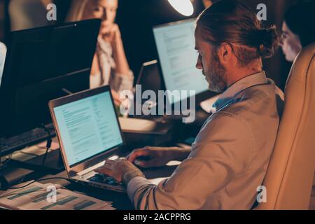 Profile side view portrait of nice attractive focused concentrated guy coworkers programming solving it tech task at night preparing report at work Stock Photo