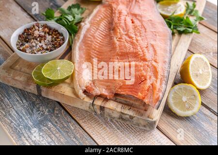 Close-up fresh appetizing salmon steak. Spices, lemon, fresh parsley and ice. Rustic background. Organic food. Stock Photo