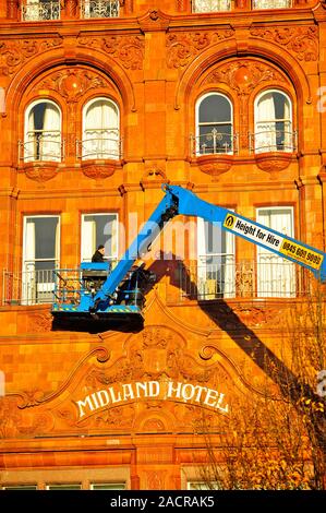 Two men on a hydraulic platform working on the front of the Midland Hotel in bright late afternoon winter sunshine,Manchester,UK Stock Photo