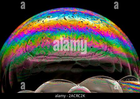 Soap bubble iridescence. Iridescence is the property of certain surfaces to change colour depending on the angle of light refraction or reflection, or Stock Photo