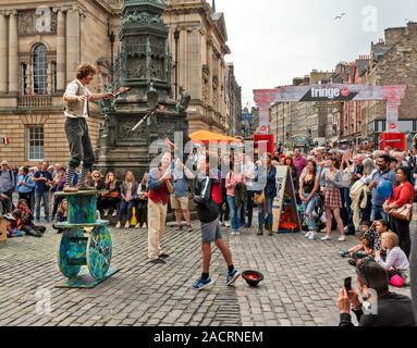 EDINBURGH SCOTLAND THE FRINGE STREET PERFORMERS A BALANCING ACT AND YOUNG MEMBER OF THE PUBLIC THROWING A FLAMING TORCH TO THE PERFORMER