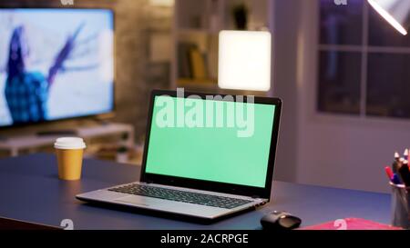 Desktop computer with green screen on home office. Businessman in the background. Stock Photo