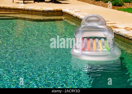 One empty inflatable plastic air raft floating in a gunite swimming pool on a bright sunny summer day with copy space Stock Photo