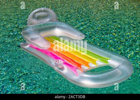 One empty inflatable plastic air raft floating in a concrete swimming pool on a bright sunny summer day. Stock Photo