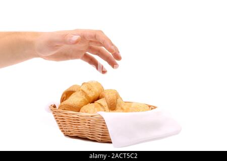 Hand reaches for the croissants in a basket. Stock Photo