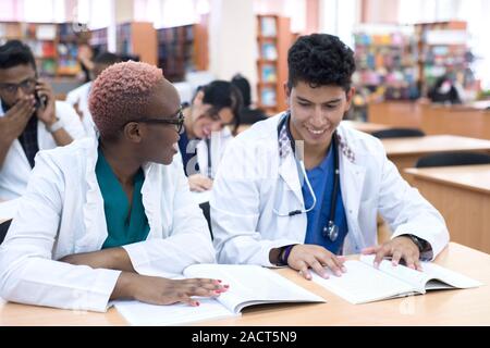 medical education, health care, people and medicine concept - group of happy doctors or interns with mentor meeting and taking notes at hospital Stock Photo