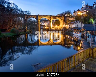 The floodlit railway viaduct reflected in the River Nidd at dusk in Knaresborough North Yorkshire England Stock Photo