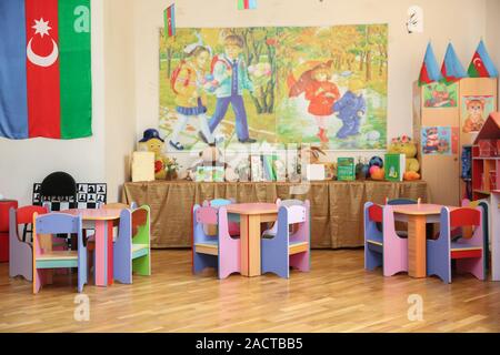 empty tables . refectory of a school for children with chairs and tables without people . School kindergarden nursery dining room . children's Stock Photo