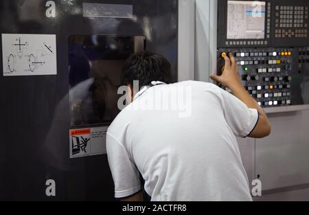 Industrial worker input data to operate cnc machine Stock Photo