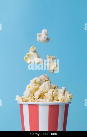 Falling popcorn in box isolated on blue. Stock Photo
