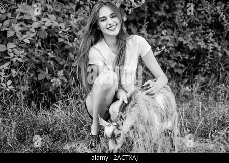 Protect animals. Veterinarian occupation. Treating animals at farm. Woman play cute goat. United with nature. Animals law. Girl and goat green grass. Farm and farming concept. Village animals. Stock Photo