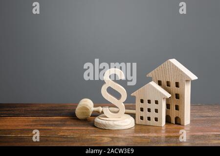Wooden houses and paragraph figurine with judge hammer. Litigation in housing and real estate disputes. Norms and rules for construction, maintenance. Stock Photo