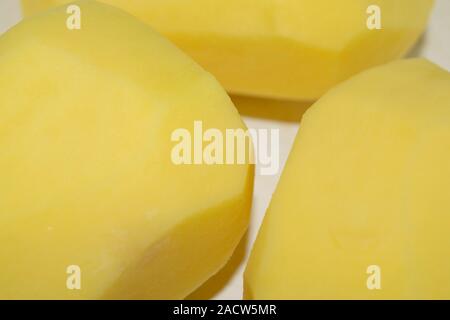 Three peeled potatoes in a white plate. Home cooking. Close up. Stock Photo