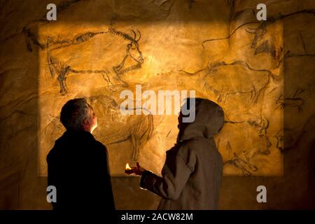 Prehistoric cave paintings. Palaeontologists looking at prehistoric depictions of animals on the walls of a cave. Photographed in the Cave of Niaux, F Stock Photo