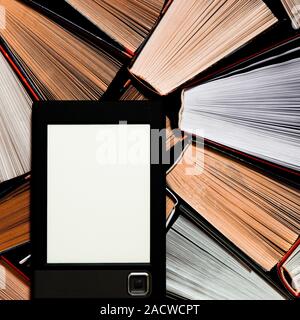 The e-book with a clean white screen rests on the open multi-colored books. ready to read Stock Photo