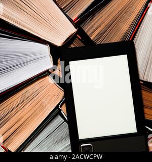 The e-book with a clean white screen rests on the open multi-colored books. ready to read Stock Photo