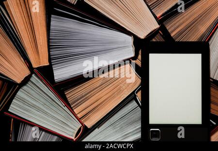 The e-book with a clean white screen rests on the open multi-colored books. ready to read Stock Photo
