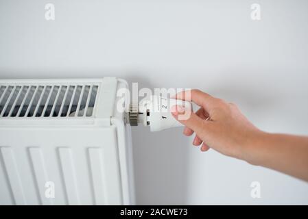 Woman Hand Adjusting The Knob Of Heating Radiator. The valve from the radiator - Heating. Hand adjusting thermostat valve of heating radiator Stock Photo